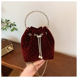Close-up of burgundy velvet bucket bag with beaded details and silver ring handle