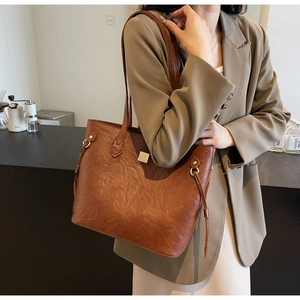 Details einer karamellbraunen Ledertasche mit seitlichem Kordelzug und Metallschnalle