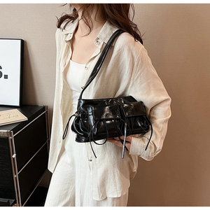 Close-up of black glossy PU leather underarm bag with double pockets and decorative straps