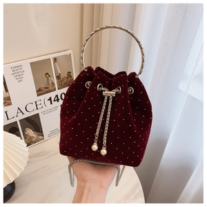 Detail of burgundy velvet bucket bag featuring silver studs and pearl drawstring accents
