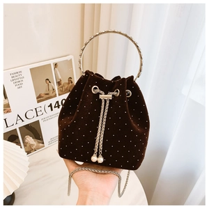 Close-up of brown velvet bucket bag with pearl embellishments and metal chain handle