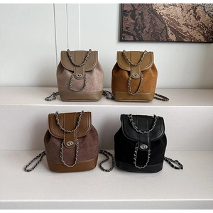 Detail of four matte leather mini backpacks with metal chain straps in neutral colors
