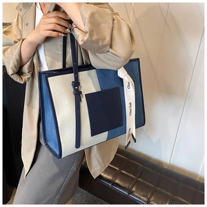 Detail view of large denim patchwork tote bag with stylish Chan'zab ribbon and leather patch