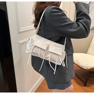 Close-up of a white patent leather shoulder bag featuring pleated details and twin pockets