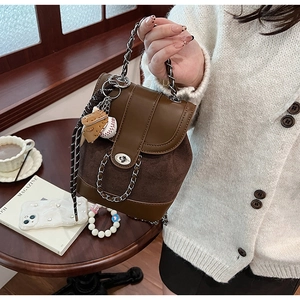 Detail of vintage matte brown mini backpack with silver chain and baseball charm decor