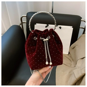 Detail of burgundy velvet bucket bag with white polka dots and silver carved handle
