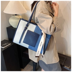 Detail view of denim patchwork tote bag showing color blocks and leather pocket styling