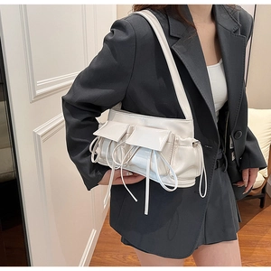 Close-up of cream PU shoulder bag featuring glossy finish and utility pockets on grey blazer