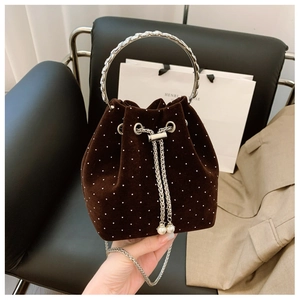 Detail of brown velvet bucket bag featuring pearl polka dots and silver metal handle