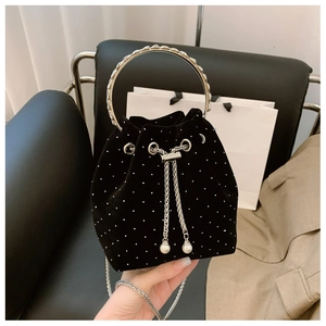 Detail of black velvet bucket bag with white bead embellishments and silver ring handle
