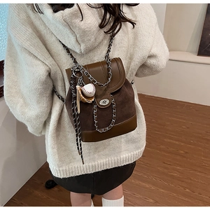 Detail of a brown frosted leather mini backpack with metal chain and baseball charm