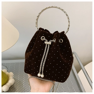 Close-up of brown velvet bucket bag with polka dots, metal handle, and pearl drawstring