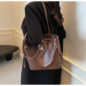 Braune Shopper-Tasche aus Kunstleder mit Vintage-Textur an der Schulter in einem Raum