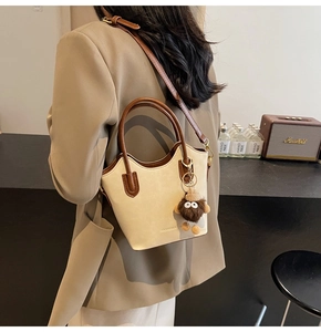 Dettaglio di una borsa a secchiello bicolore retrò abbinata a un blazer color kaki
