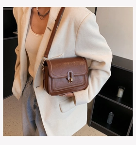 Gros plan d'un sac à bandoulière en cuir marron vintage avec rivets dorés et boucle