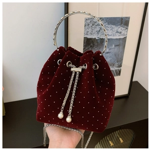 Detail view of burgundy velvet bucket bag with white pearl dots and silver ring handle
