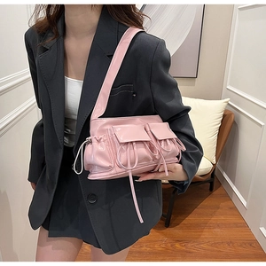 Detail of pink patent leather baguette bag featuring bow drawstring pockets and glossy finish