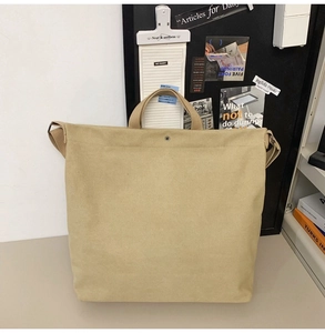 Detailed view of large canvas tote bag with metal snap button and wide shoulder strap