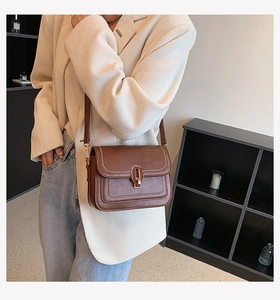 Détail d'un sac bandoulière marron vintage avec fermoir doré et coutures décoratives