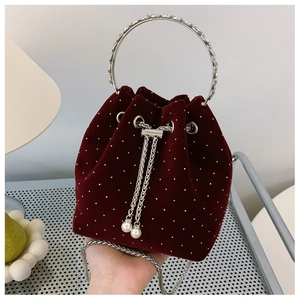 Close-up of burgundy velvet bucket bag with rhinestone dots and metal ring handle