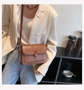Détail du sac bandoulière marron vintage avec surpiqûres blanches et fermoir doré