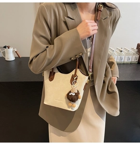 Dettaglio della borsa a secchiello beige e marrone con ciondolo a mostro e tracolla
