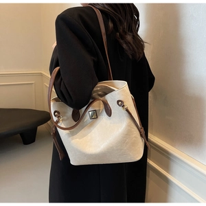 Detailansicht der cremeweißen Leder-Eimertasche mit braunem Griff und Goldschnalle