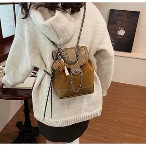 Detail of tan suede mini backpack with chain strap and doll charm in vintage interior