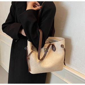 Modell trägt eine große cremefarbene Tote Bag mit dunkelbraunen Trägern und Schnalle