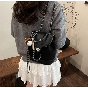 Detail of black matte leather bucket backpack with chain strap and baseball charms