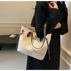 Detailansicht der Kontrastkanten und Metallschnalle an der cremefarbenen Shopper-Tasche