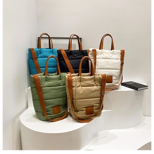 Group display of quilted puffer tote bags in five colors on a tiered white podium