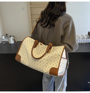 Detailansicht der beigen Reisetasche mit geometrischem Muster und braunem Lederbesatz