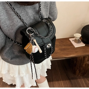 Detail of black frosted backpack featuring silver chain straps and baseball bag charm