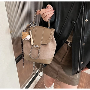 Detail of retro khaki backpack featuring mixed leather texture and baseball keychain