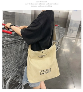 Large beige canvas messenger bag showing daily use capacity in a shopping scene
