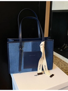Large denim patchwork tote bag with blue leather pocket and cream decorative ribbon