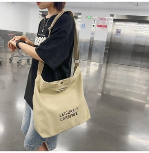 Detail view of beige canvas tote bag with adjustable strap and snap button closure