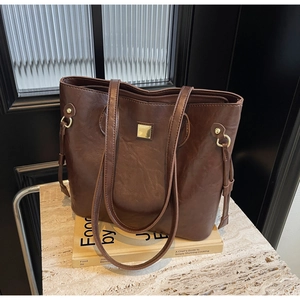 Details einer dunkelbraunen Leder-Shopper mit goldenen Metallteilen auf Steinfläche