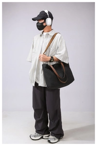 Detail of black canvas tote bag with brown leather handles and adjustable shoulder strap