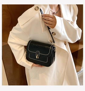 Gros plan détaillé d'un sac bandoulière en cuir noir avec surpiqûres blanches et fermoir doré