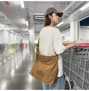 Brown canvas crossbody bag with Leisurely Carefree text, worn by a model in a shop