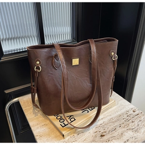 Detailansicht der großen braunen Vintage-Leder-Tote-Bag auf Marmorsockel mit Golddekor