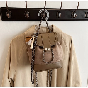 Detail of brown matte leather backpack with silver chain and baseball charms decoration