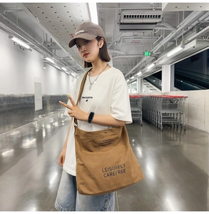 Brown canvas crossbody bag with Leisurely lettering shown in a stylish urban setting
