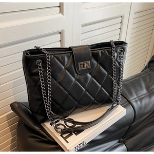 Détail du sac cabas en cuir matelassé noir avec motif losanges et bandoulière en chaîne