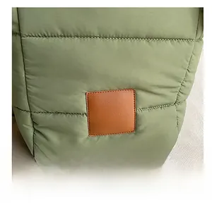 Detail of green quilted puffer bucket bag featuring a brown leather decorative patch