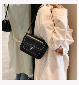 Détail du sac bandoulière noir avec surpiqûres blanches et fermoir doré en vue miroir