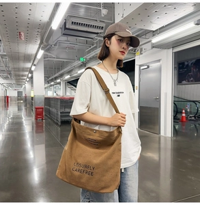 Adjustable wide strap and metal buckle detail on a large brown canvas messenger bag