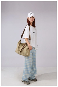 Detailed side view of khaki canvas tote bag with adjustable shoulder strap on a model